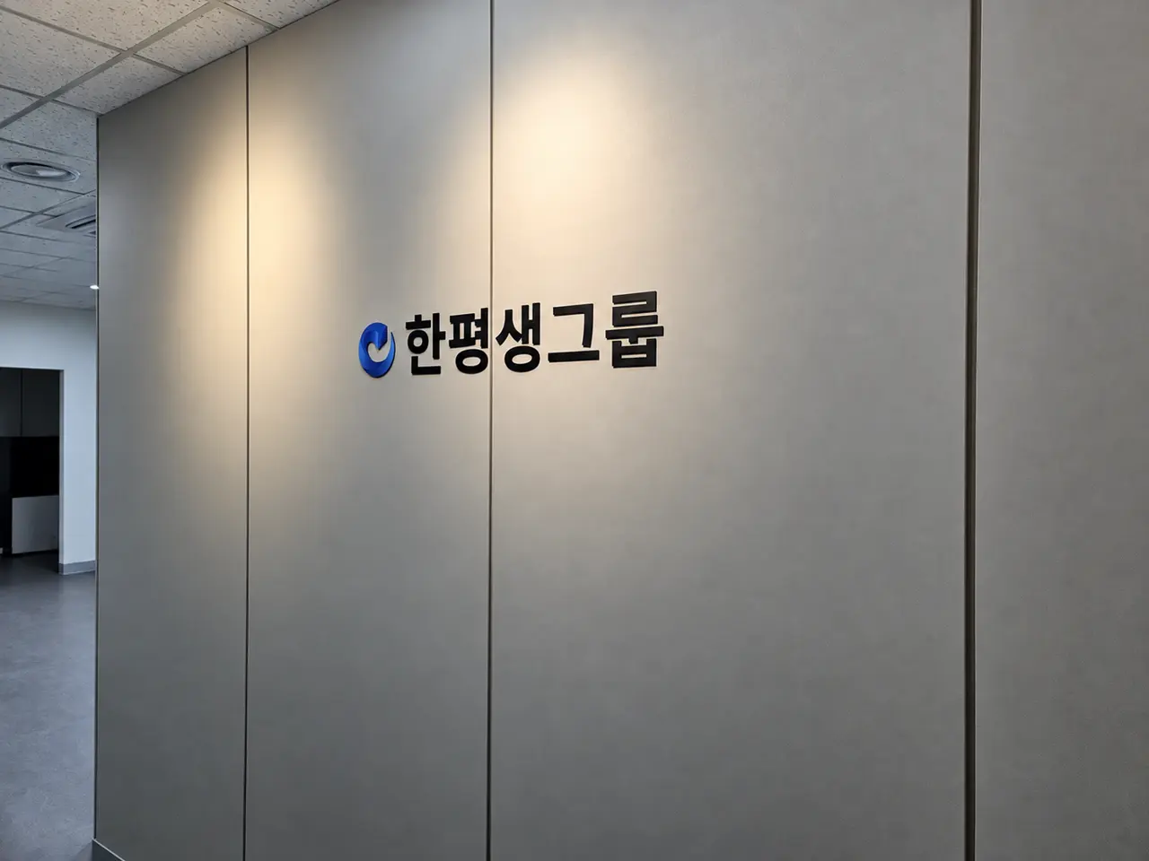 그레이 벽면 위 한평생그룹 입체 로고