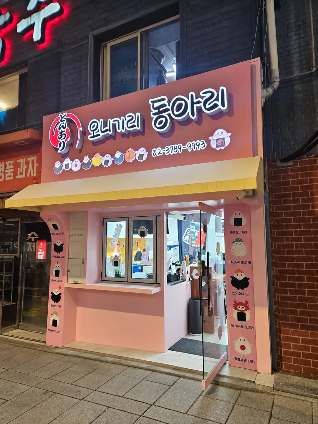핑크색 파사드와 조명 간판을 설치한 야간 외관